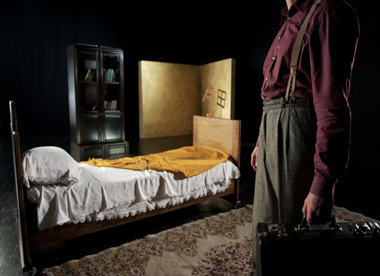 a man standing by an empty bed in a darkened room 