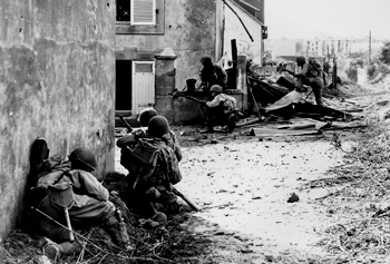photograph of soldiers crouched behind buildings.