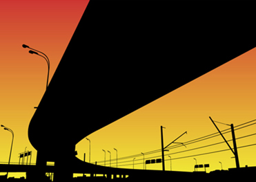 a black freeway overpass against a red and orange sky.